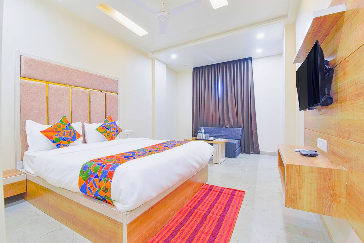 Een moderne hotelkamer met een groot bed, een bureau, een televisie en een badkamer op de achtergrond.