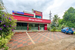 A modern building with a red facade, labeled "Abrigo Residency" and "Pooneil" on the signage. - Fabhotel Abrigo Residency (Devikolam)