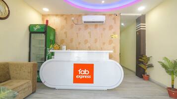 A reception area with a white reception desk labeled "fab express," a green Sprite refrigerator, and a clock on the wall.