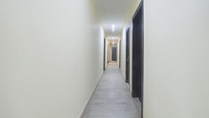 Un pasillo estrecho y bien iluminado con piso de concreto y paredes lisas, que conduce a una puerta al final.
