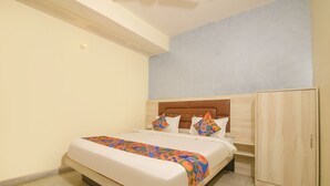 Un dormitorio con cama, cabecera, armario y pared de color claro.