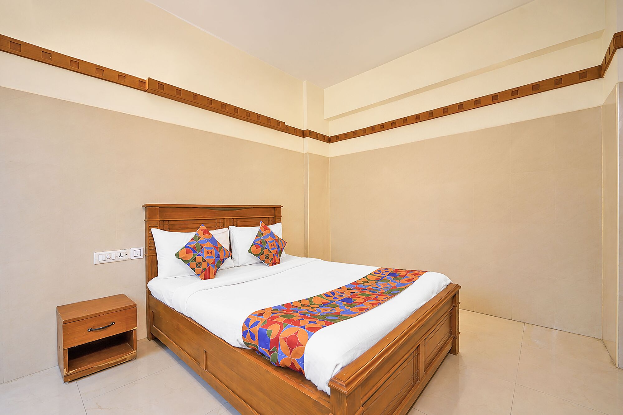 A neatly made bed with a wooden headboard, a bedside table, and a patterned bedspread.