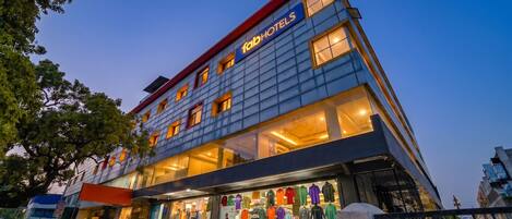 A hotel with multiple floors, large windows, and a storefront with clothing items on display.