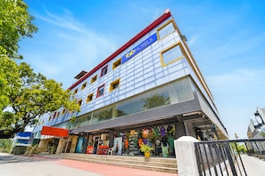 Ein mehrstöckiges Hotel mit Glasfassade, einem roten und blauen Schild und einer Auslage mit KleidungsstĂŒcken.