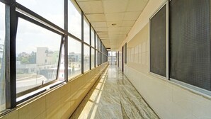 Un largo pasillo con ventanas amplias a un lado y una pared con una pantalla al otro.