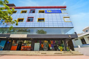 Ein GebĂ€ude mit blauer Fassade, einem Schild mit der Aufschrift 'fab hotels' und einer Schaufensterfront mit KleidungsstĂŒcken.