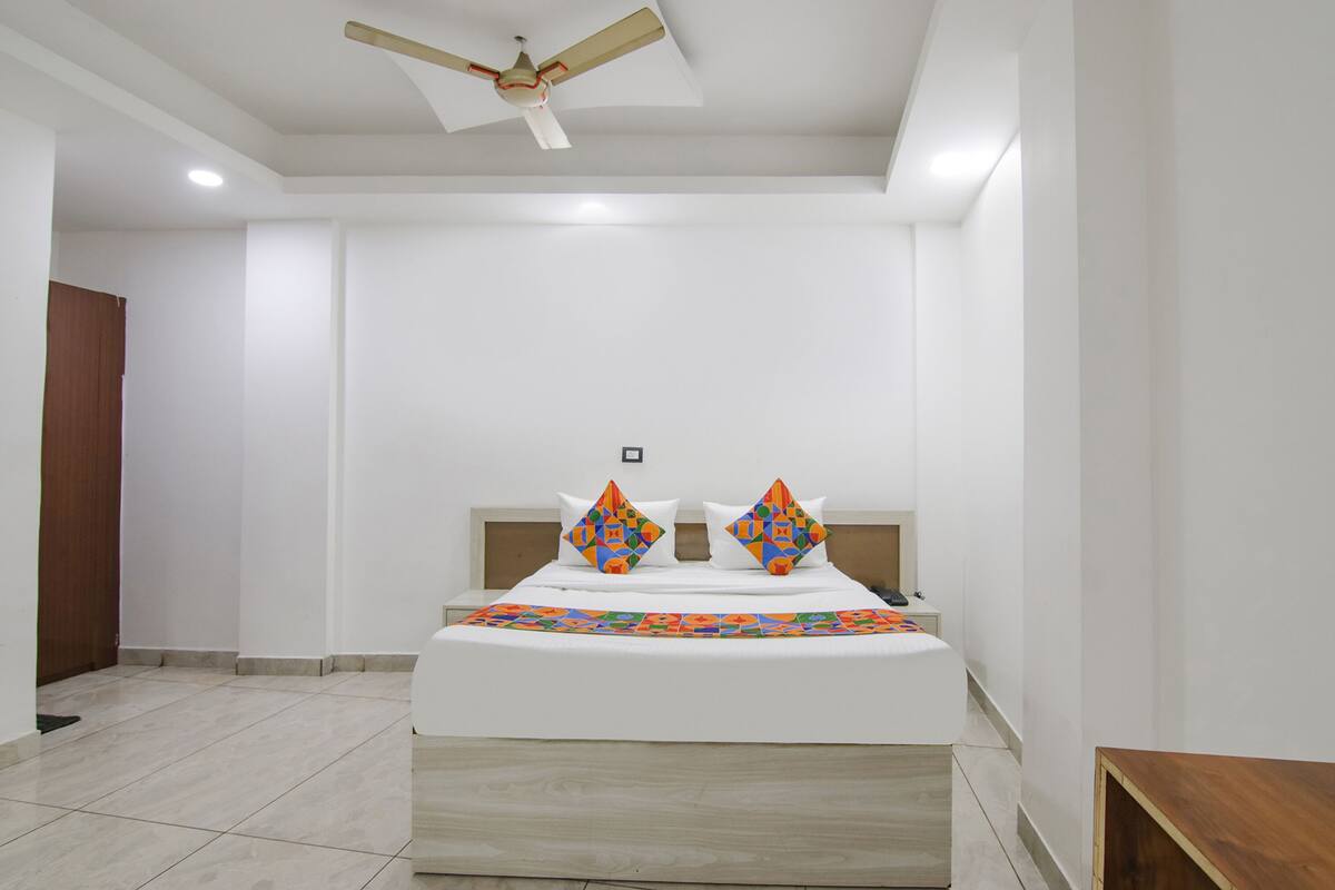 A bedroom with a bed, a ceiling fan, and a wooden door.