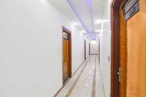 A hotel hallway with wooden doors, a marble floor, and a sign indicating the direction to the lobby. - FabHotel The Grand Heritage (Gurugram)