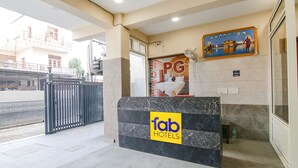 A hotel reception desk with a marble counter, a 'fab hotels' sign, and a 'PG' sign above the door. - Fabhotel Gg Residency (Mohali)