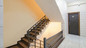 A staircase with a metal railing, a door with a number, and a tiled floor. - Fabhotel Gg Residency (Mohali)