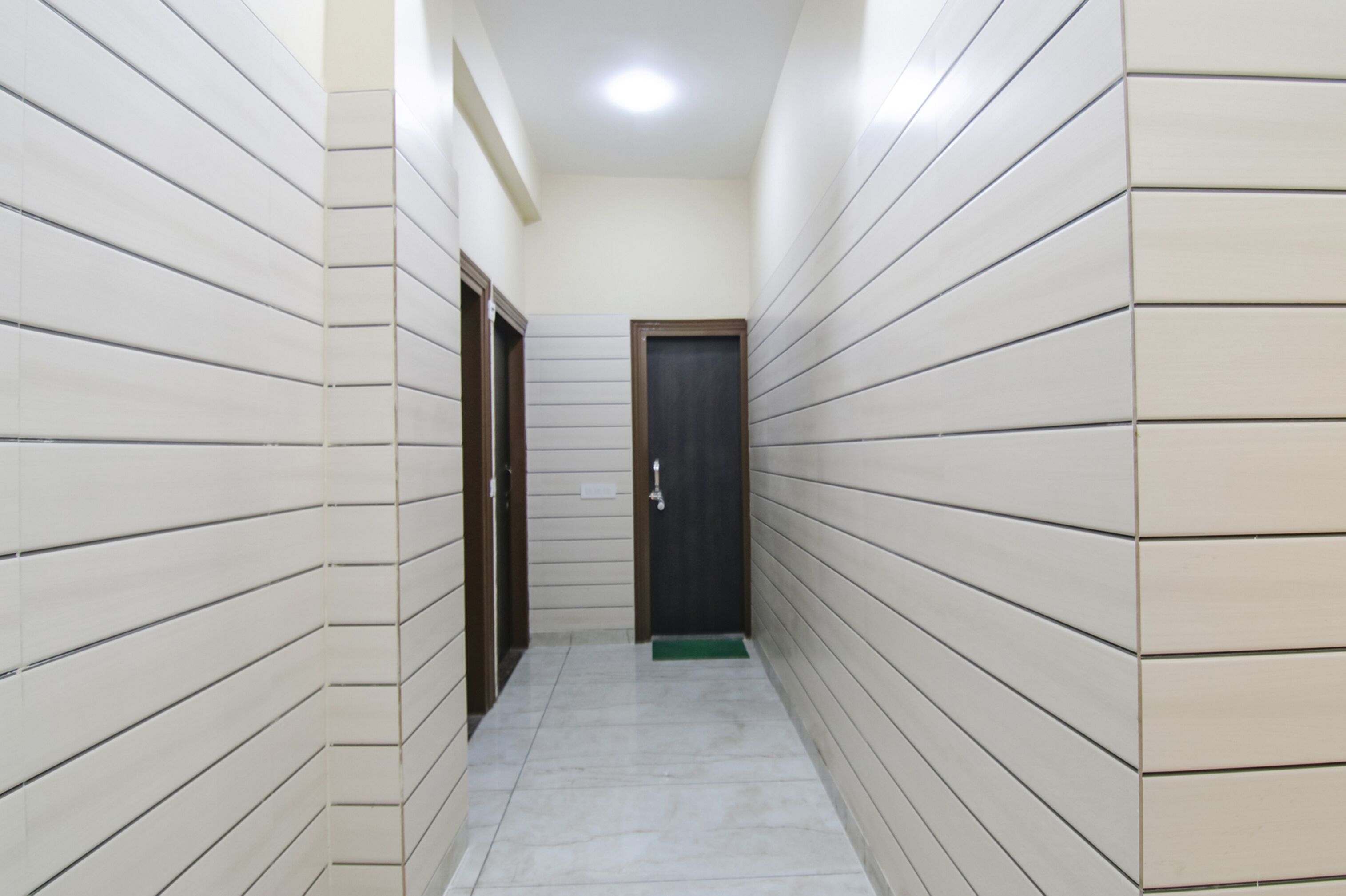 A narrow hallway with tiled walls and a door at the end.