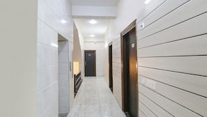A narrow hallway with tiled walls and floors, a door at the end, and an elevator on the right. - Fabhotel Gg Residency (Mohali)