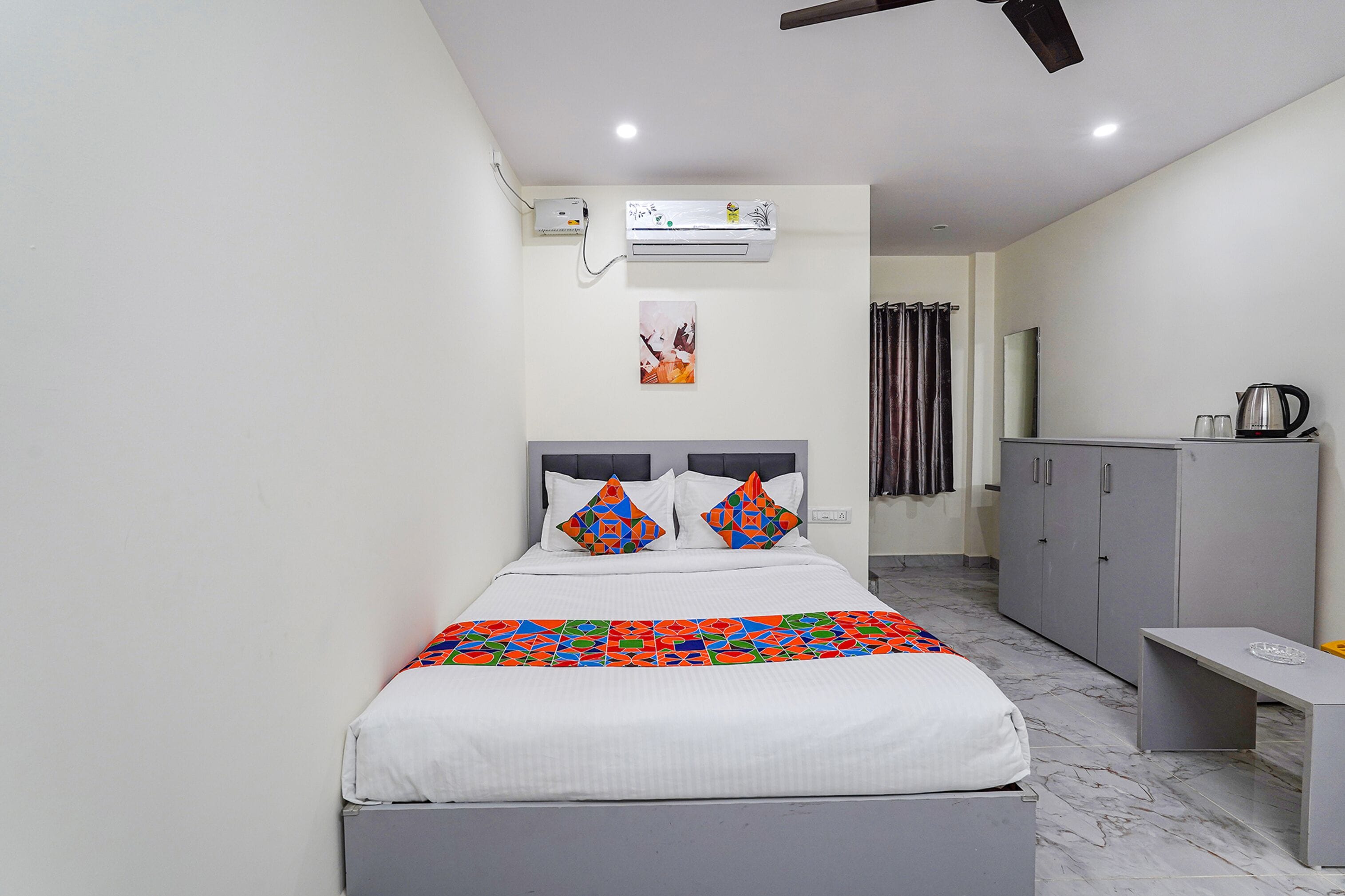 Una camera da letto moderna con un letto, condizionatore d'aria, opere d'arte e un armadio grigio.