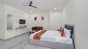 A modern bedroom with a bed, a ceiling fan, a TV, and artwork on the walls. - FabHotel Ivory Pearl Koramangala Bangalore (Bengaluru)