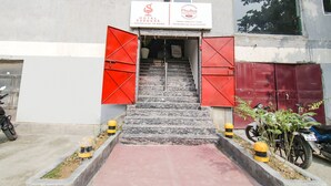 A hotel entrance with a signboard, red shutters, and a staircase leading inside. - Fabhotel Ssensse (New Delhi)