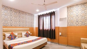 A bedroom with a bed, a ceiling fan, a window with curtains, and a wooden wardrobe. - Fabhotel Ssensse (New Delhi)