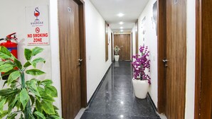 A hotel corridor with wooden doors, a no smoking sign, and potted plants. - Fabhotel Ssensse (New Delhi)