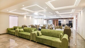 A modern conference room with a green sofa, tables, chairs, and a polished floor. - Fabhotel Prime Royal Court (Ludhiana)