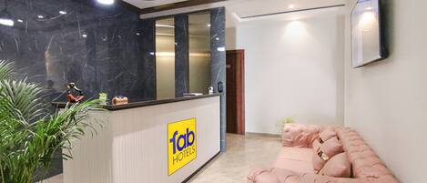 A reception area with a marble counter, a plush pink sofa, and a ceiling fan.