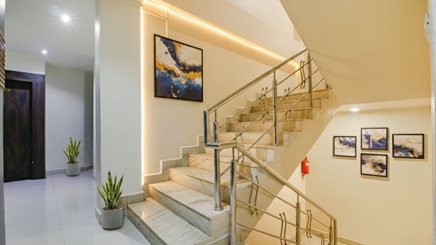 A modern staircase with metal railings, a potted plant, and artwork on the walls. - Fabhotel Royal Palace Ii (Bhopal)