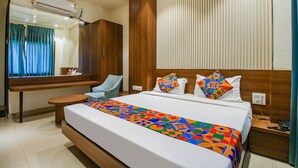 A modern hotel room with a large bed, a wooden headboard, a bedside table with a phone, and a mirror above the bed. - Fabhotel Royal Palace Ii (Bhopal)