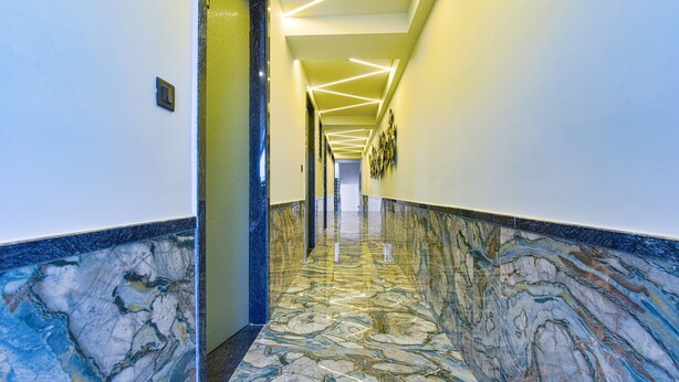 A hallway with marble flooring and a modern light fixture. - FabHotel Shubh Hari (Jaipur)