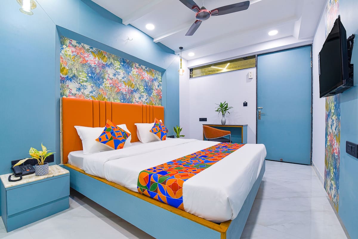 Un dormitorio moderno con una cama grande, un ventilador de techo y una obra de arte floral en la pared.