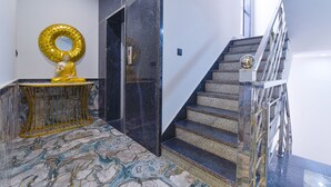 A marble-floored lobby with a golden statue, a mirror, and a staircase with metal railings. - FabHotel Shubh Hari (Jaipur)
