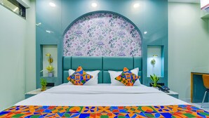 A modern bedroom with a large bed, a floral-patterned headboard, and a colorful geometric rug. - FabHotel Shubh Hari (Jaipur)