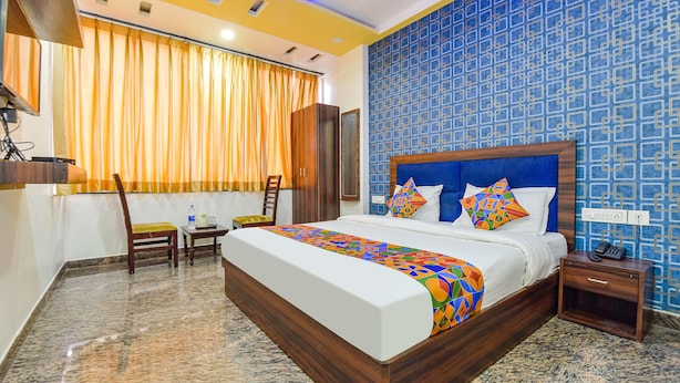 A hotel room with a large bed, a desk, a chair, and a wardrobe. - FabHotel Diamond Inn (Jaipur)