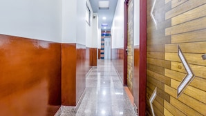 A hallway with a polished floor, a wooden wall with a chevron design, and a door with a chevron sign. - FabHotel Diamond Inn (Jaipur)