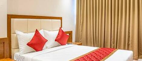 Una cama bien hecha con estructura de madera y ropa de cama blanca, incluyendo almohadas rojas y un detalle en rojo.