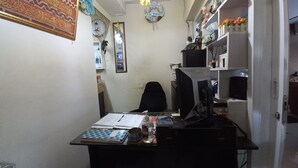 A small office with a desk, computer, and shelves with decorative items. - OYO Life  93023 Kost Bulan Karawang (Karawang)