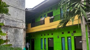A two-story building with a green and yellow facade, multiple windows, and a balcony. - OYO Life  93023 Kost Bulan Karawang (Karawang)