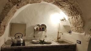 Eine Küche mit einem rustikalen Steingewölbe, einem Wasserkocher, einem Spülbecken und einem Geschirrgestell.