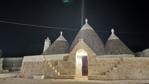 Ein Steinhaus mit einem zentralen Rundbogenportal und drei Kegeldächern.