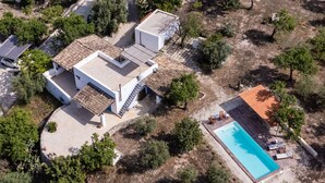 Vue aérienne d’une propriété résidentielle dotée d’une piscine, d’un patio couvert et d’un garage séparé.