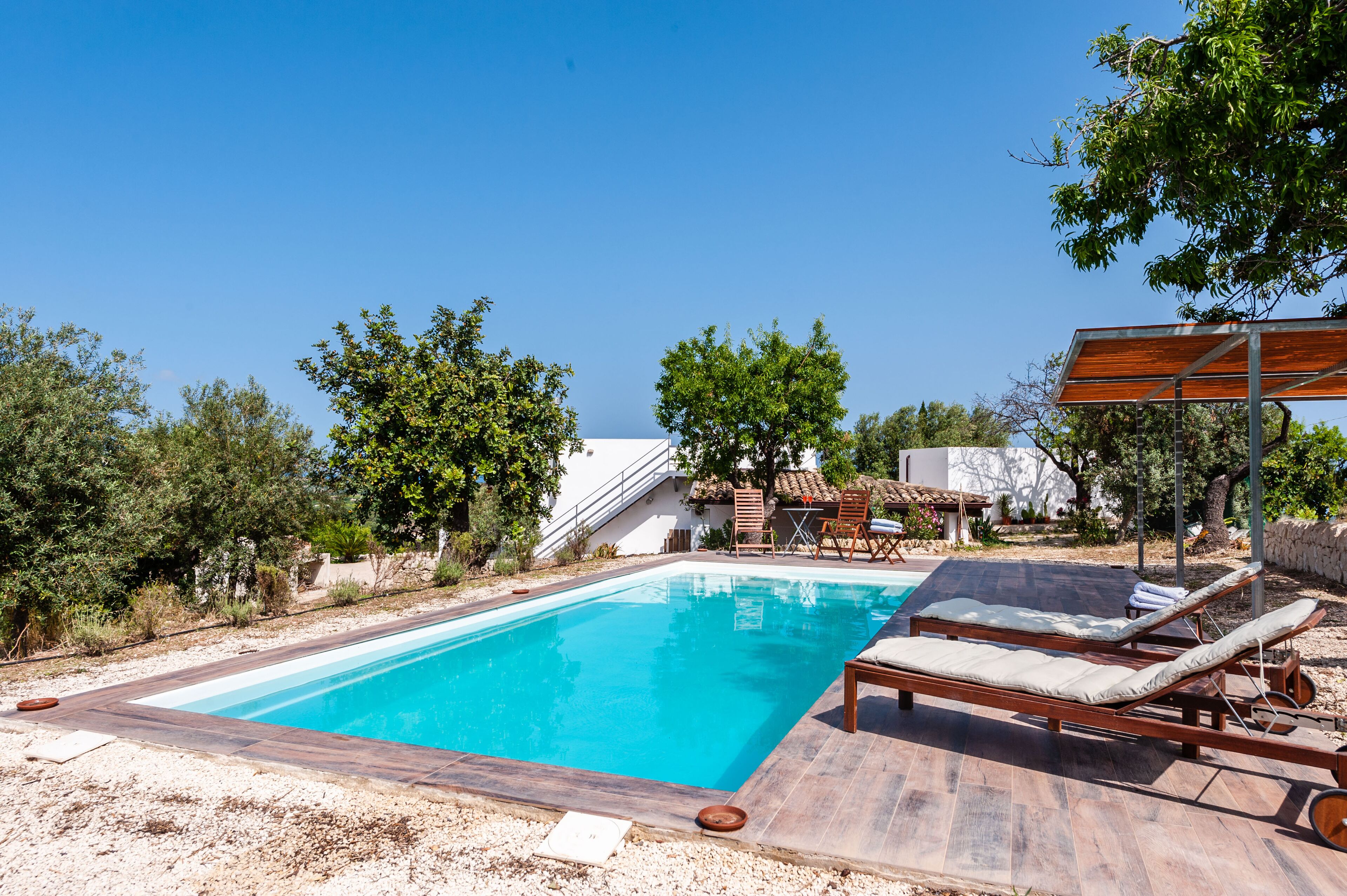 Ein rechteckiger Swimmingpool mit Liegestühlen und einer Holzterrasse.