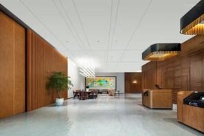 Eine moderne Lobby mit Empfangsschalter, Sitzgelegenheiten und einem großen abstrakten Gemälde an der Wand.
