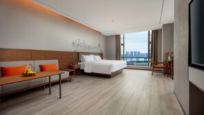 Een moderne hotelkamer met een bed, een bank, een tafeltje en een televisie.