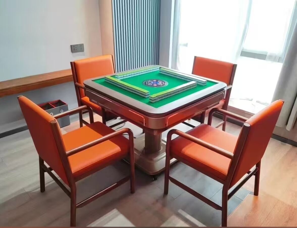 A room with a square table, four orange chairs, and a green carpet.