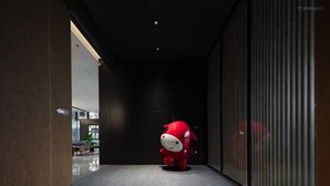 Een hal met een rode mascotte, een donker plafond en een glazen scheidingswand.
