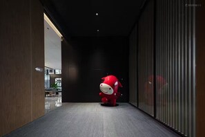 Een hal met een rode mascotte, een donker plafond en een glazen scheidingswand.