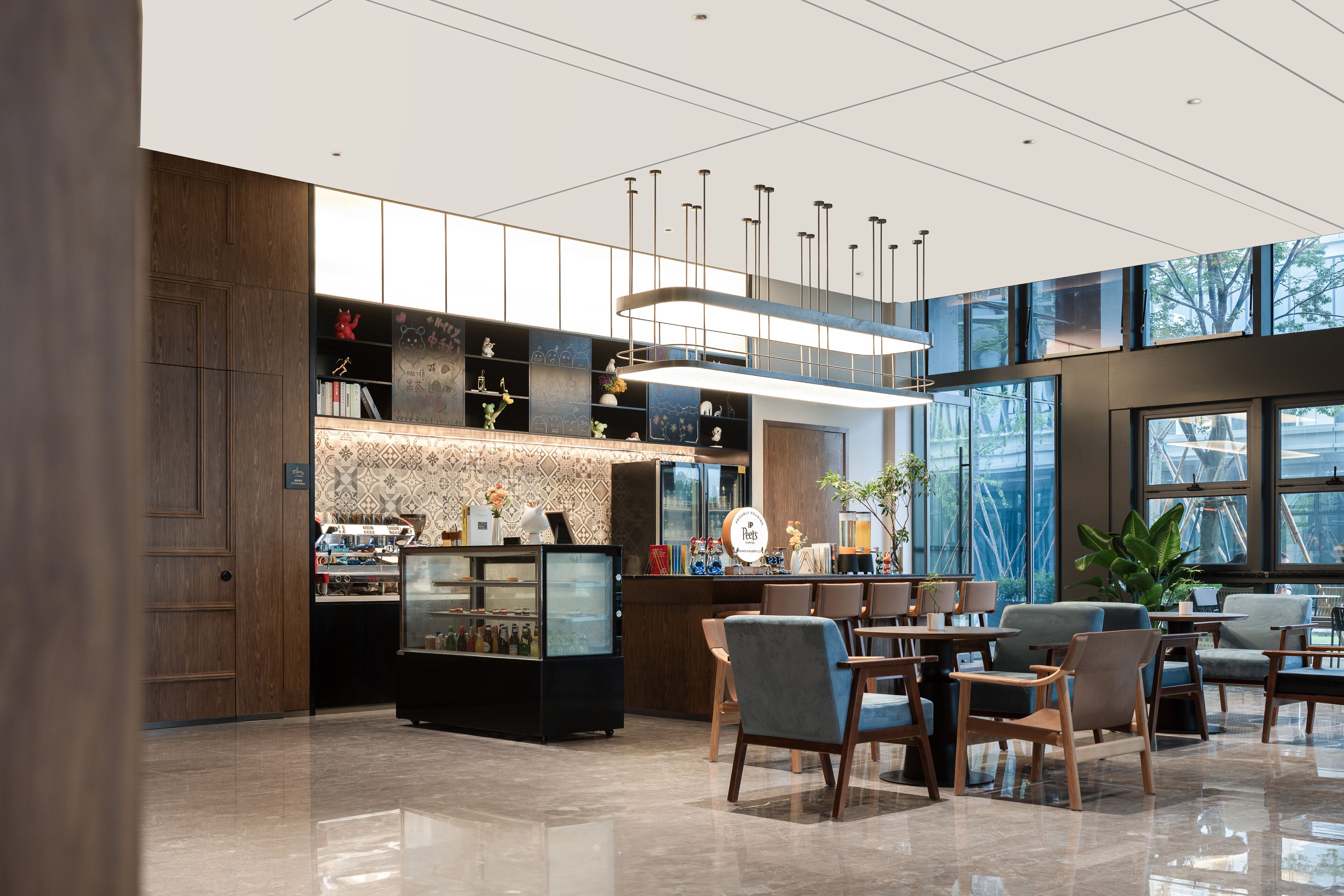 A modern hotel lobby with a central bar area, seating arrangements, and large windows offering views.
