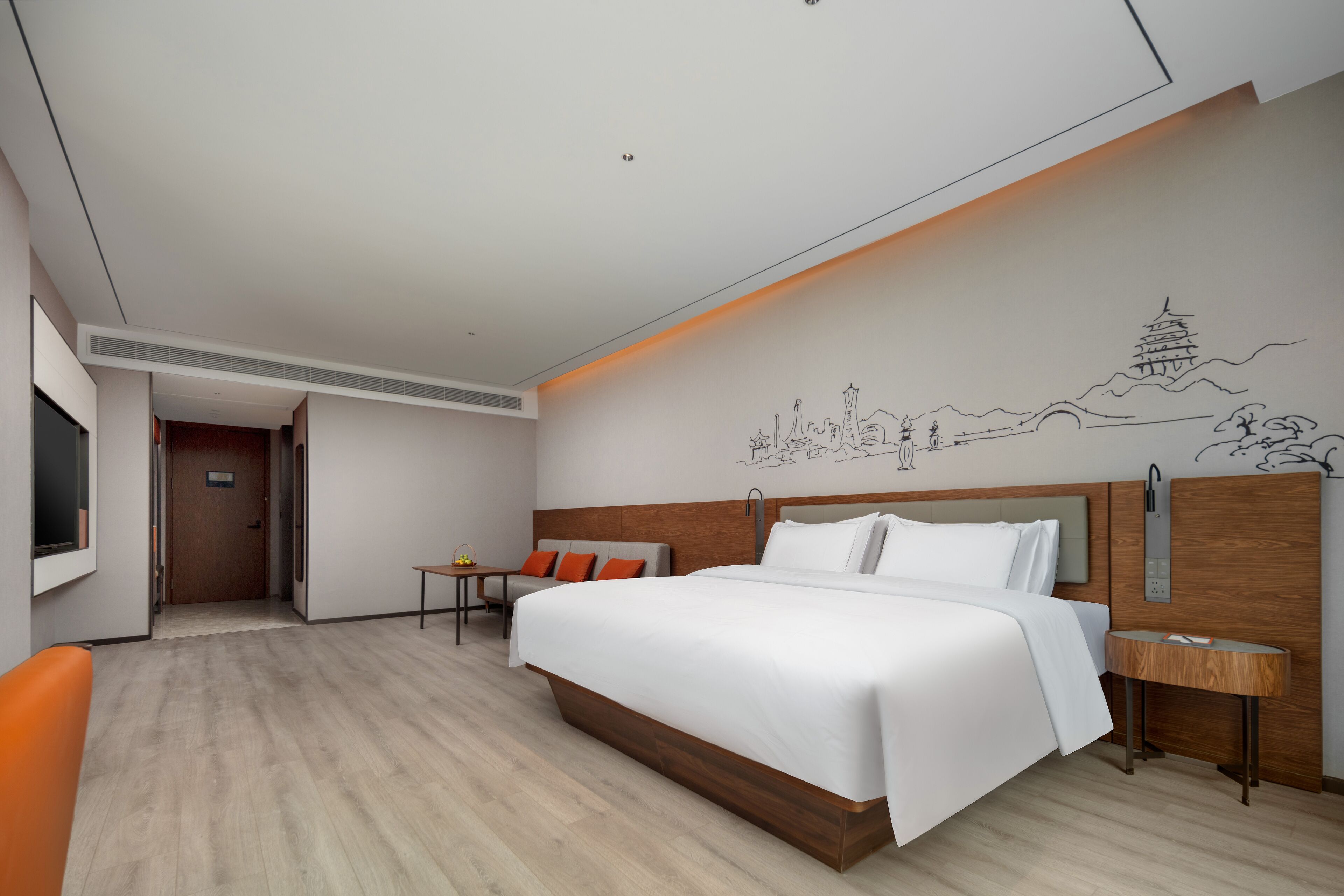 A modern hotel room with a large bed, a small table, and a wall mural.