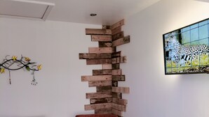 Une pièce avec deux fauteuils rouges, une œuvre d’art murale en bois, un tableau encadré et un tapis en fourrure sur le sol.