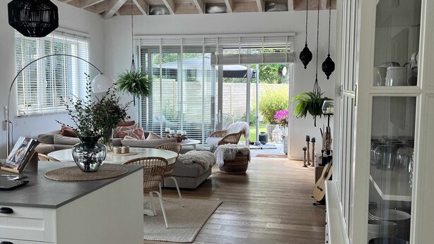 Amplia sala de estar con techo de madera, ventanas grandes y vista al jardín.