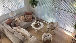 Una sala de estar moderna con un sofá modular, una mesa de centro redonda, un sillón de mimbre y un otomano mullido.