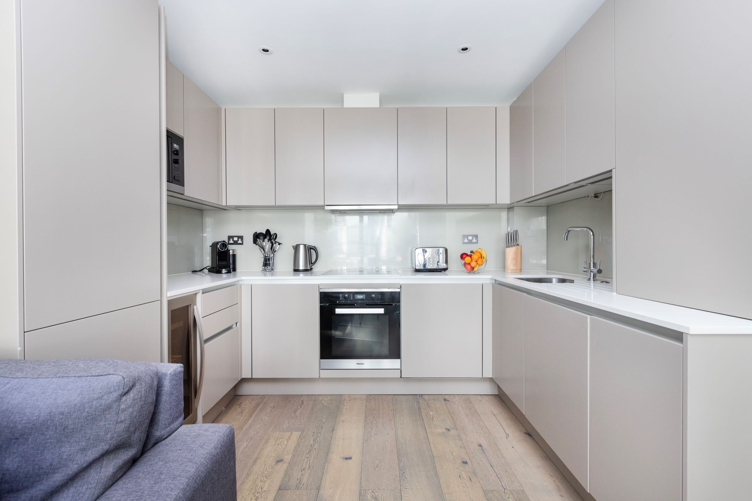 A modern kitchen with white cabinets, a built-in oven, a coffee maker, and a toaster.