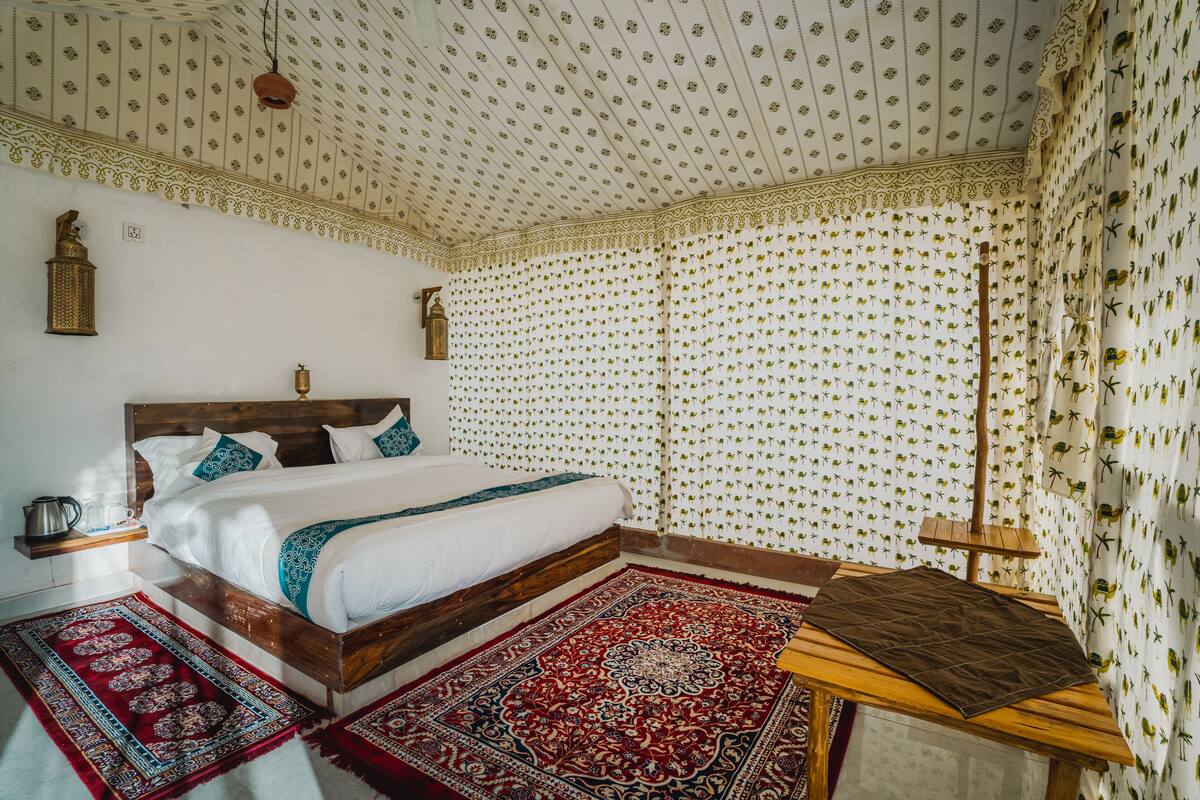 A bedroom with a wooden bed, patterned curtains, and a red and blue rug.